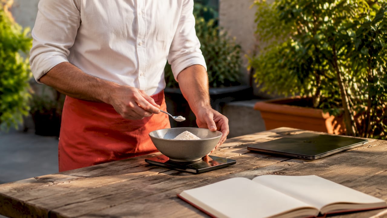 Mani che pesano gli ingredienti per calcolare il costo della ricetta