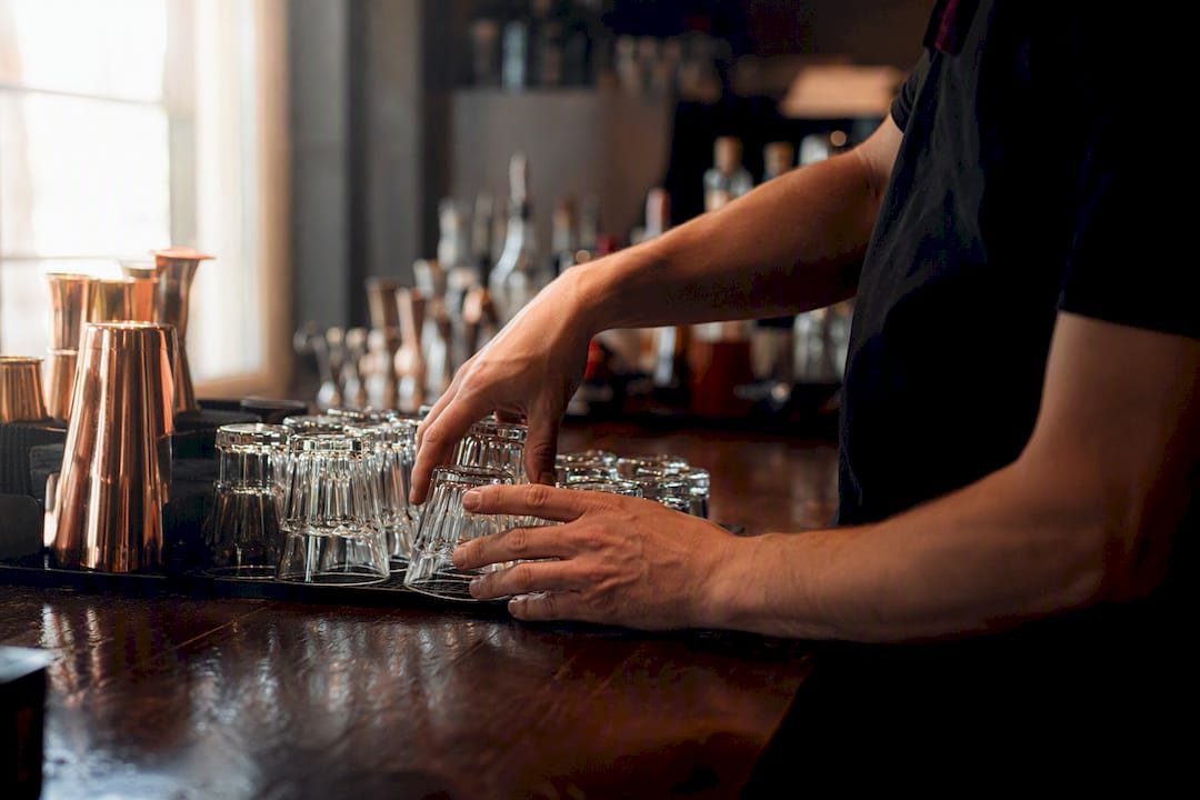 Mani del barista che sistemano i bicchieri al bancone