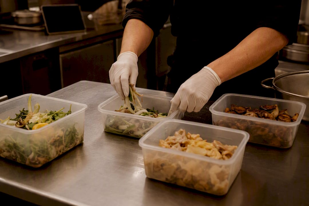 Mani che valutano la quantità di spreco alimentare in cucina