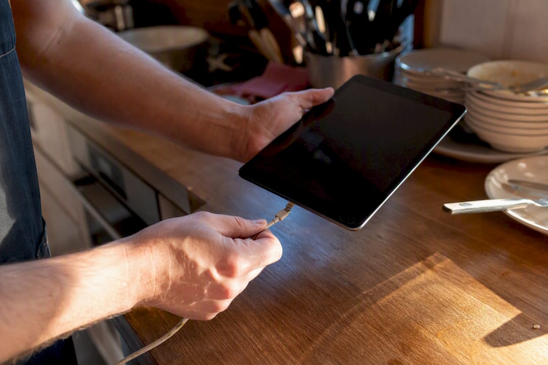 Mani che collegano un tablet al caricabatterie in un ristorante