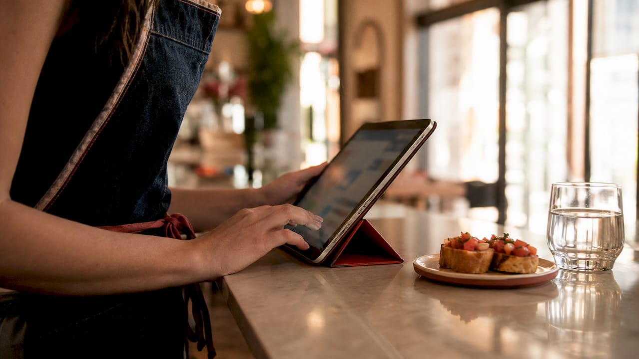 Mani che utilizzano un software gestionale per pizzeria su tablet