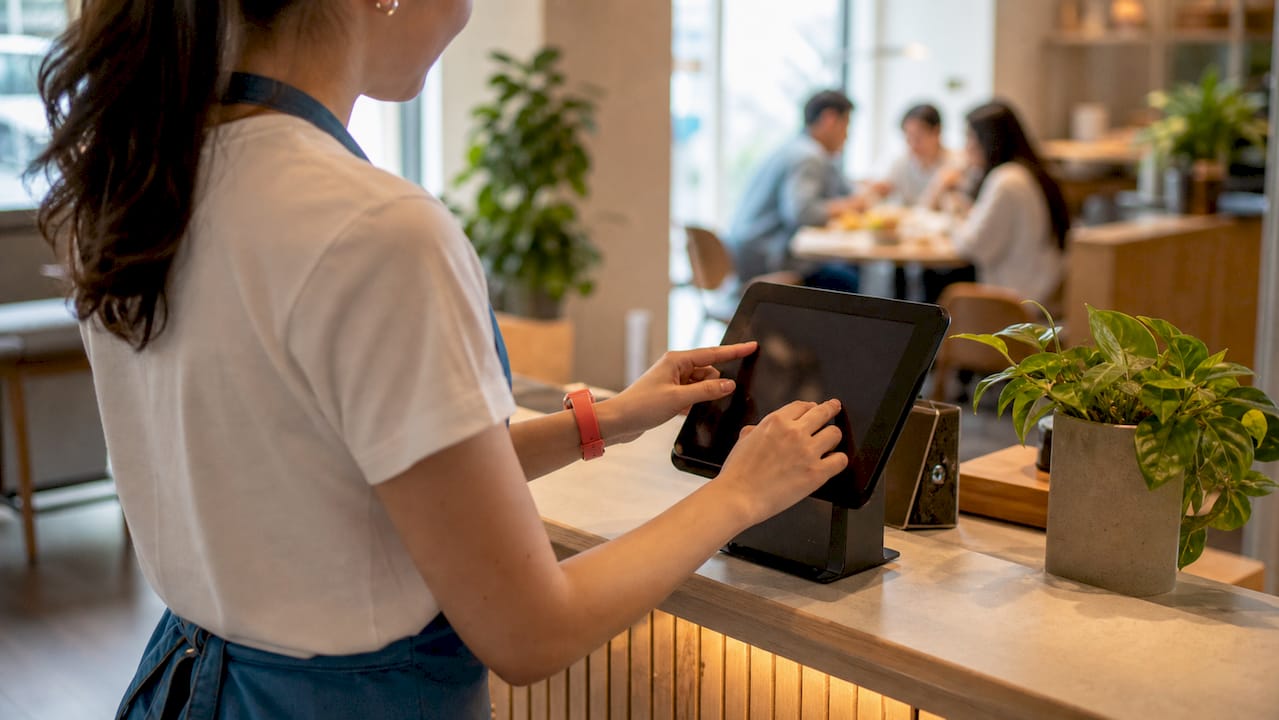 Mani che utilizzano una cassa automatica per un pagamento veloce in un locale fast casual.