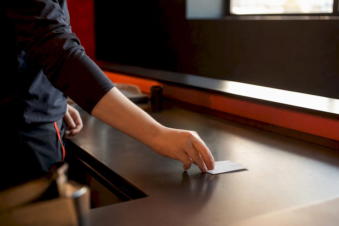 Mani che mostrano il gettone per ritirare l'ordine al banco